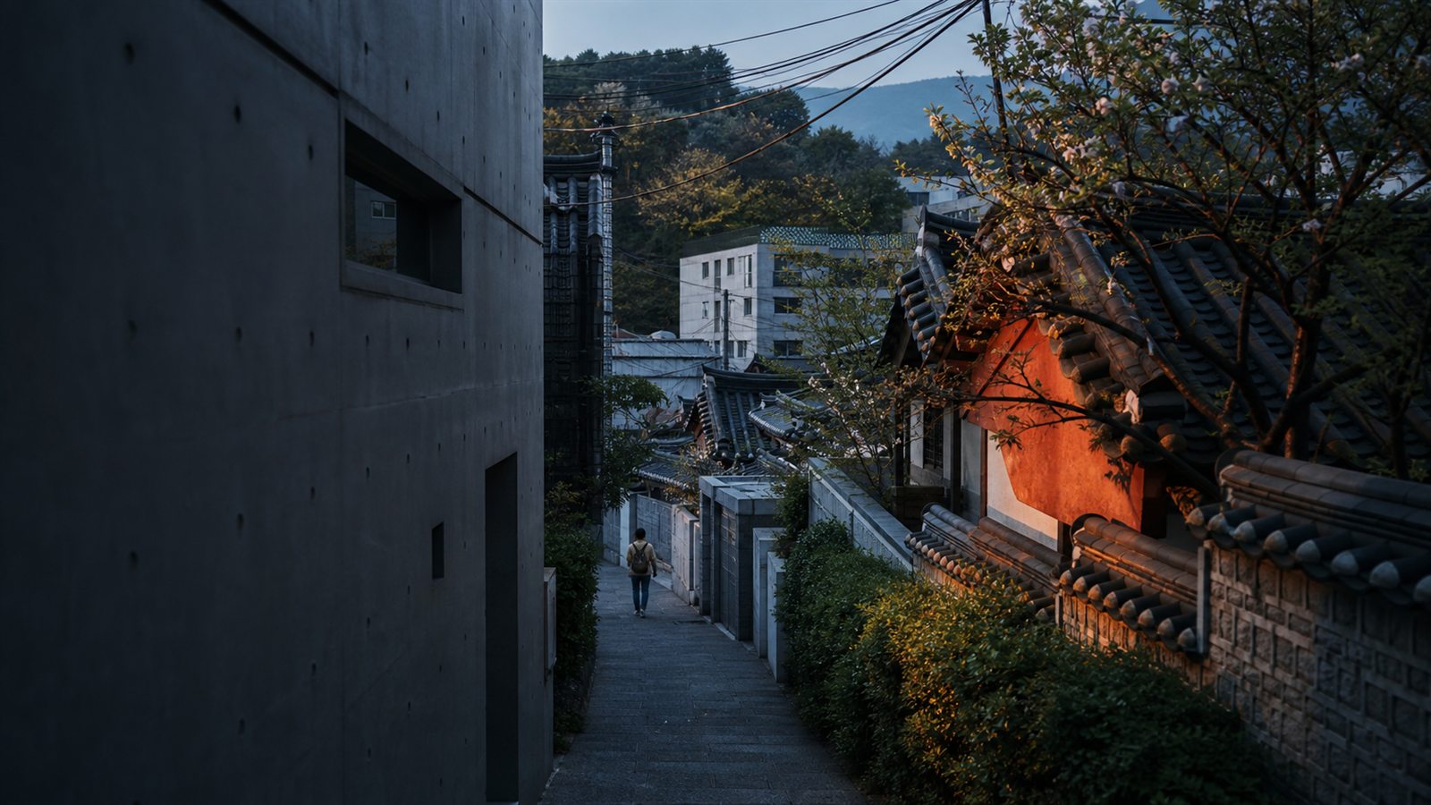 A quiet Seoul lane between contemporary architecture and traditional hanok roofs at dawn