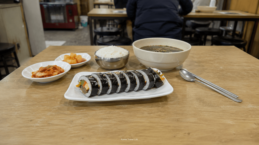 Affordable Korean Meal in Seoul Affordable Korean meal with kimbap, rice, soup, kimchi, and side dishes at a small local restaurant in Seoul