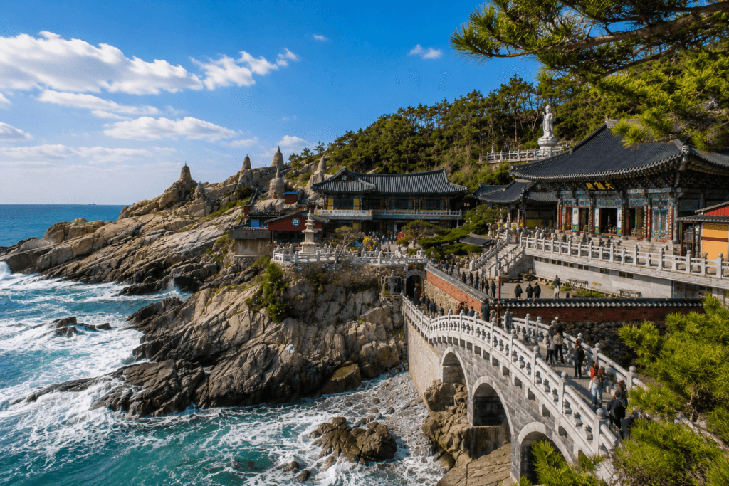 Coastal viewpoint at Haedong Yonggungsa Temple with stone bridge, rocky cliffs, blue sea, and temple rooftops