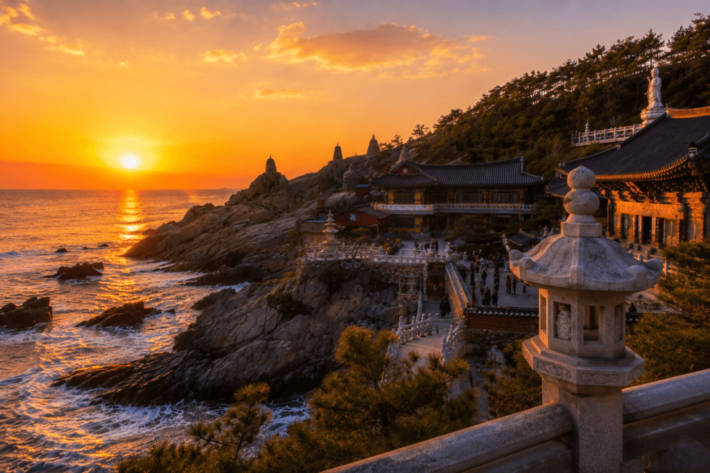 Sunrise over the East Sea at Haedong Yonggungsa Temple with stone lantern, rocky coastline, and warm golden light