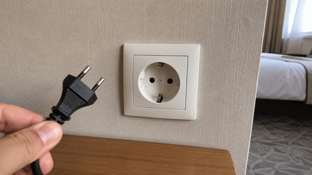 Korean Type F wall outlet with a two-round-pin electrical plug in a hotel room