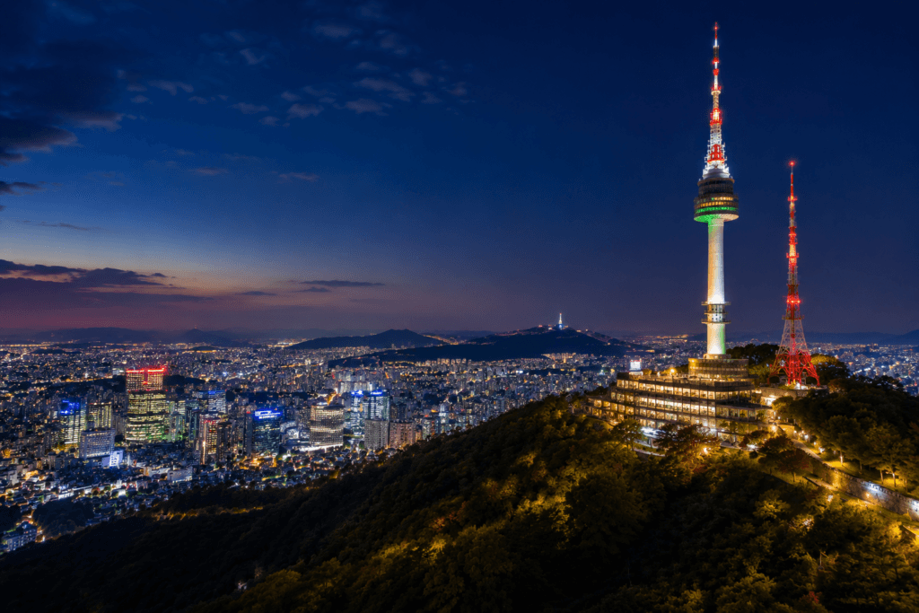 N Seoul Tower illuminated at night with Seoul city lights spreading below Namsan Mountain