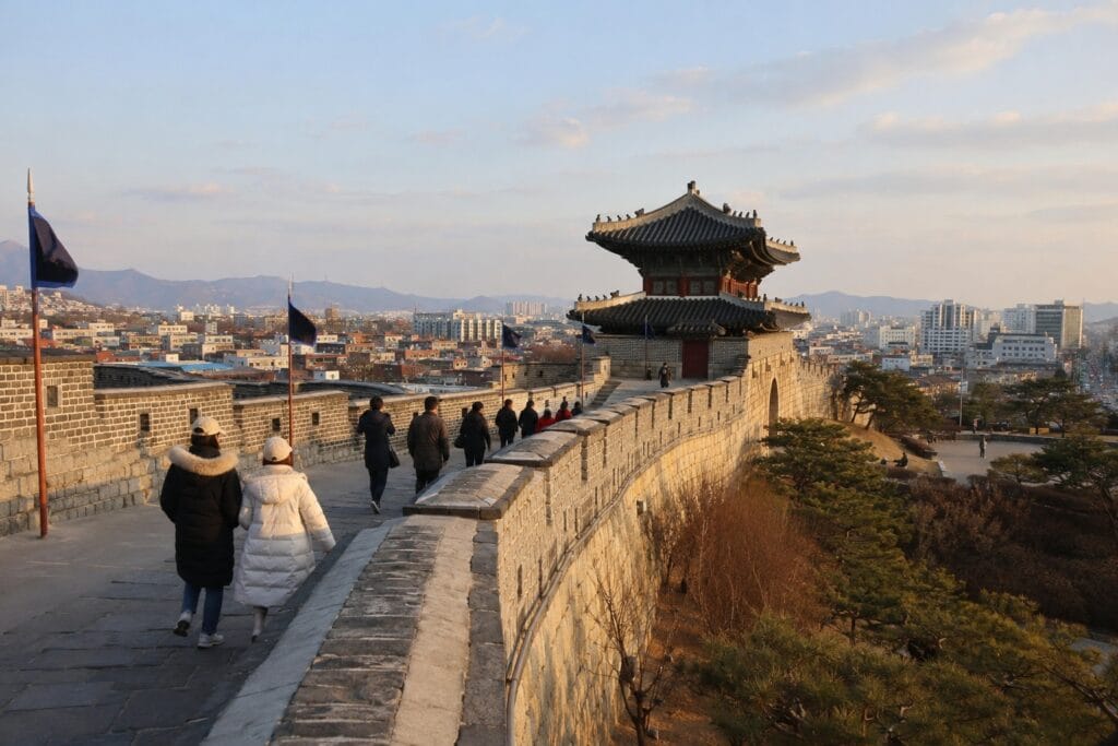Visitors walking along Suwon Hwaseong Fortress with the city in the background