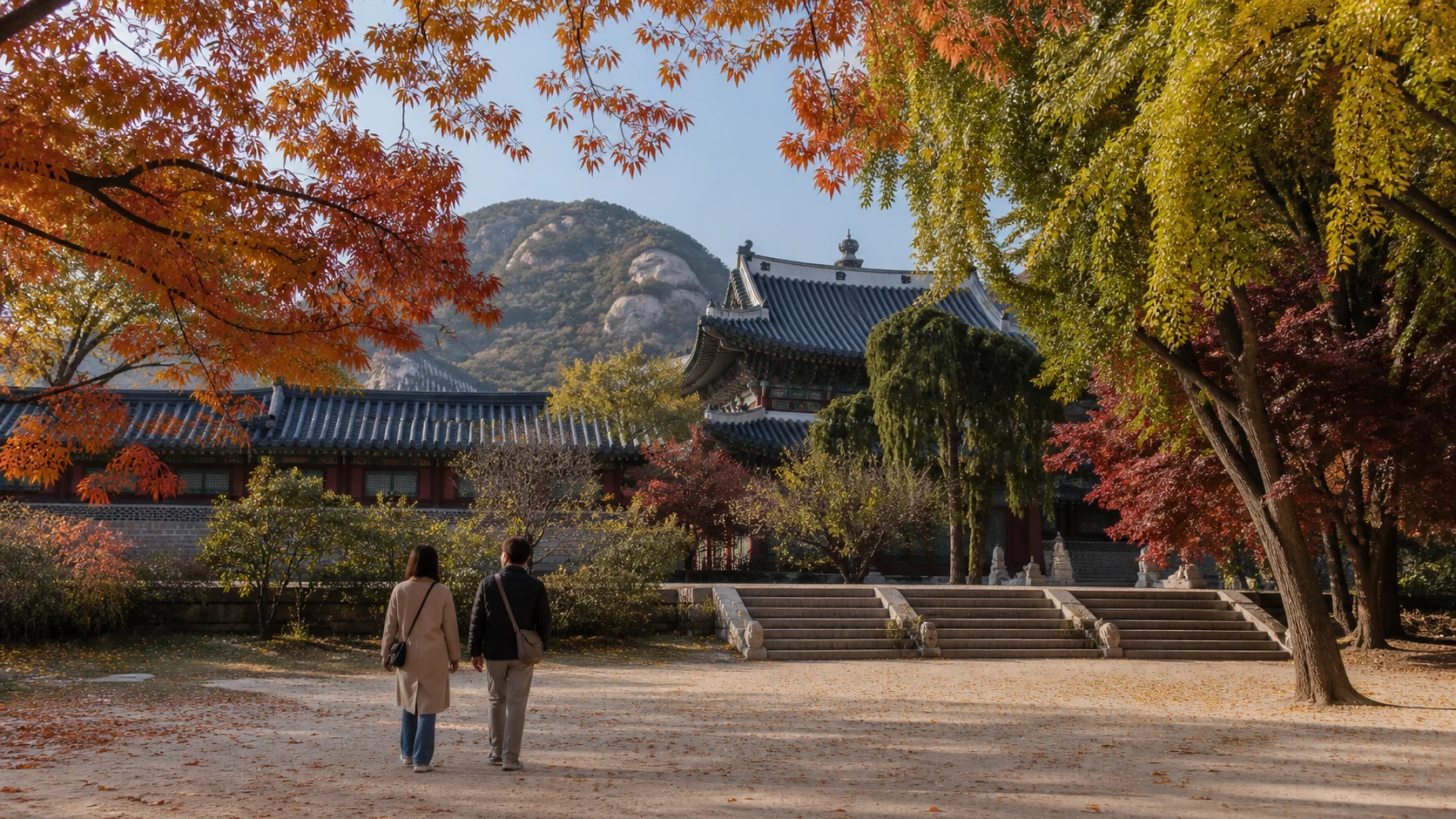 Travelers walking beneath autumn trees at a traditional Korean heritage site in October
