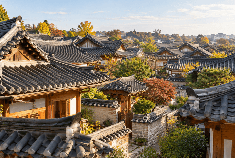 Gray curved hanok roofs and wooden eaves with autumn trees in a Jeonju-inspired neighborhood
